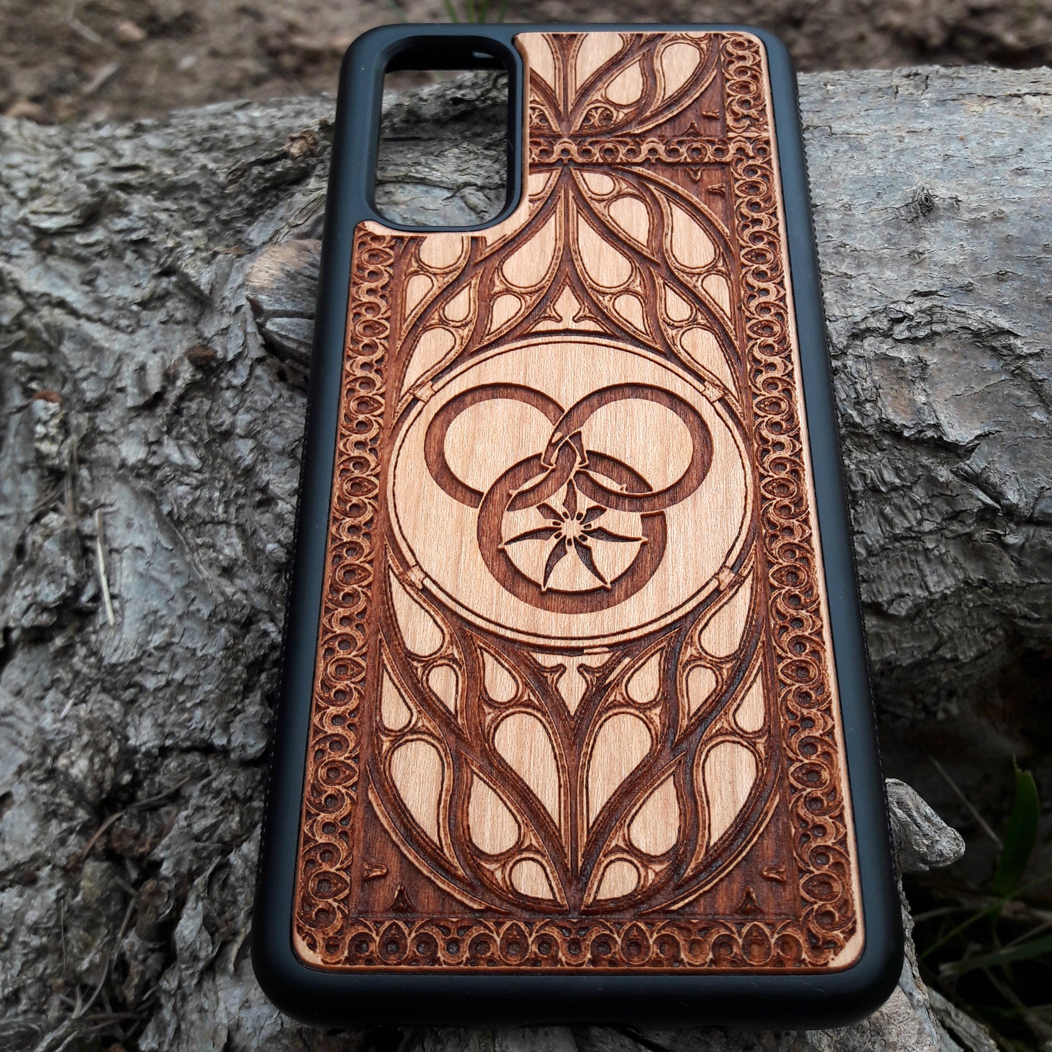 Wheel of Time-inspired wood phone case, laser-engraved with the iconic Aes Sedai symbol and intricate patterns. Made from premium wood for durability and elegance, this case is compatible with iPhone , 15, 14, 13, 12, 11, Pro Max, Mini, and Samsung Galaxy S, S24, S23, S22, S21, S20 Ultra, Plus, Note 20. A perfect accessory for fans seeking a unique and protective design.