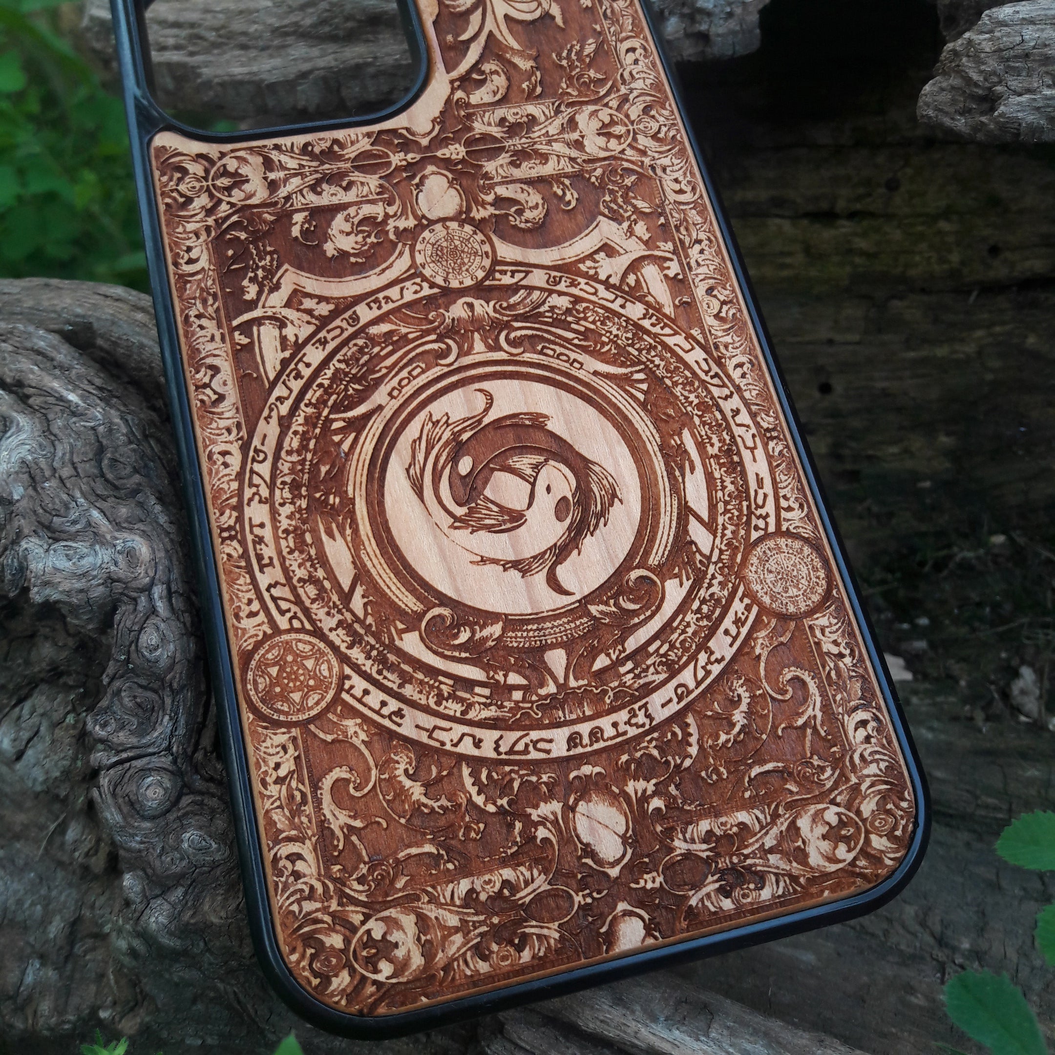 Intricately designed wood phone case featuring a yin-yang koi fish motif surrounded by detailed ornamental patterns and symbolic script. Laser-engraved for precision and durability, this case is compatible with iPhone , 15, 14, 13, 12, 11, Pro Max, Mini, and Samsung Galaxy S, S24, S23, S22, S21, S20 Ultra, Plus, Note 20. A unique and artistic accessory for those seeking elegance and protection.
