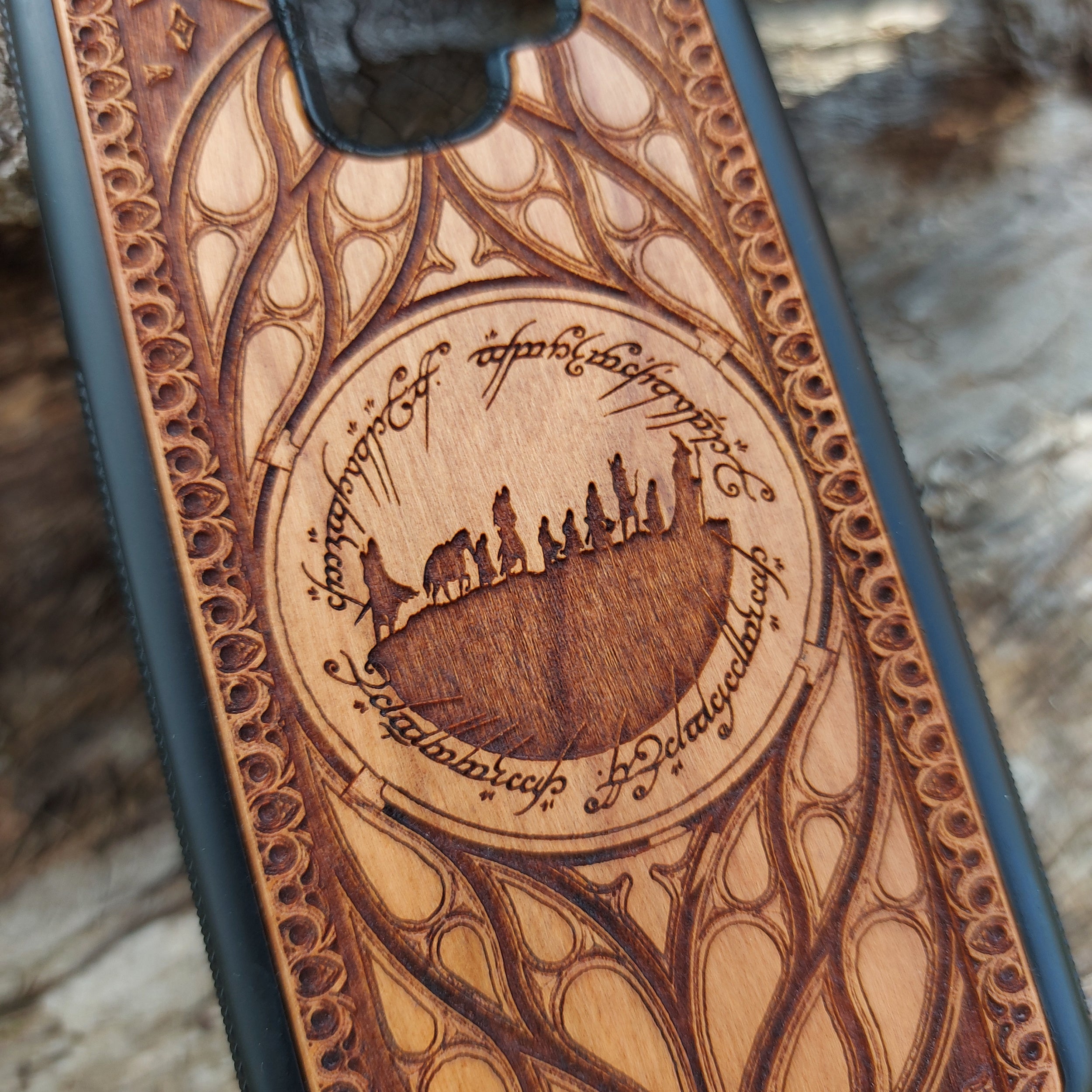 Lord of the Rings wood phone case featuring the Fellowship of the Ring silhouette surrounded by Elvish script and intricate, elegant patterns. Laser-engraved for precision and durability, this case is compatible with iPhone , 15, 14, 13, 12, 11, Pro Max, Mini, and Samsung Galaxy S, S24, S23, S22, S21, S20 Ultra, Plus, Note 20. A unique and protective accessory for Tolkien fans.