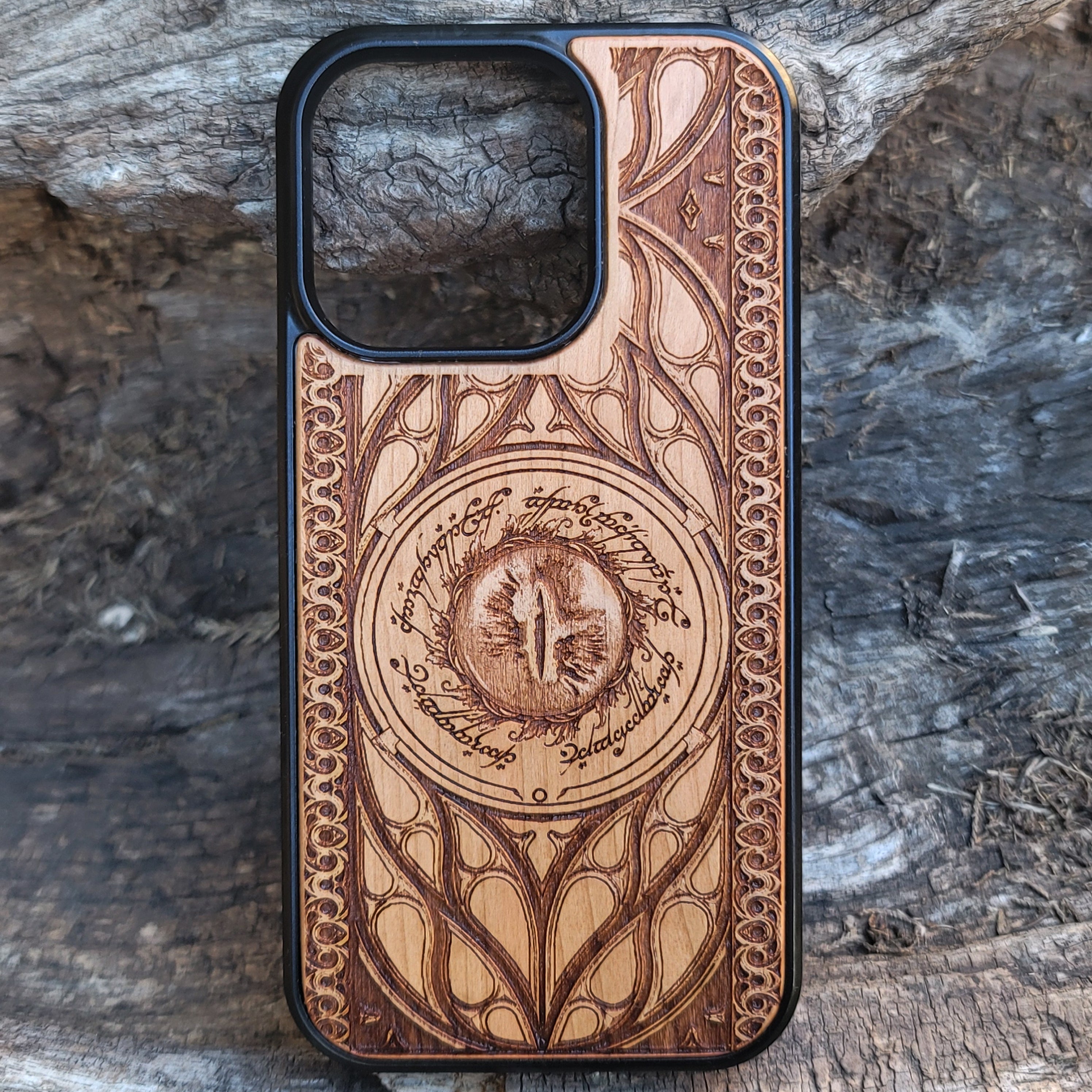Lord of the Rings wood phone case featuring the Eye of Sauron surrounded by Elvish script and intricate, elegant patterns. Laser-engraved for durability and unique artistry, this case is compatible with iPhone , 15, 14, 13, 12, 11, Pro Max, Mini, and Samsung Galaxy S, S24, S23, S22, S21, S20 Ultra, Plus, Note 20. A stunning and protective accessory for Tolkien fans.