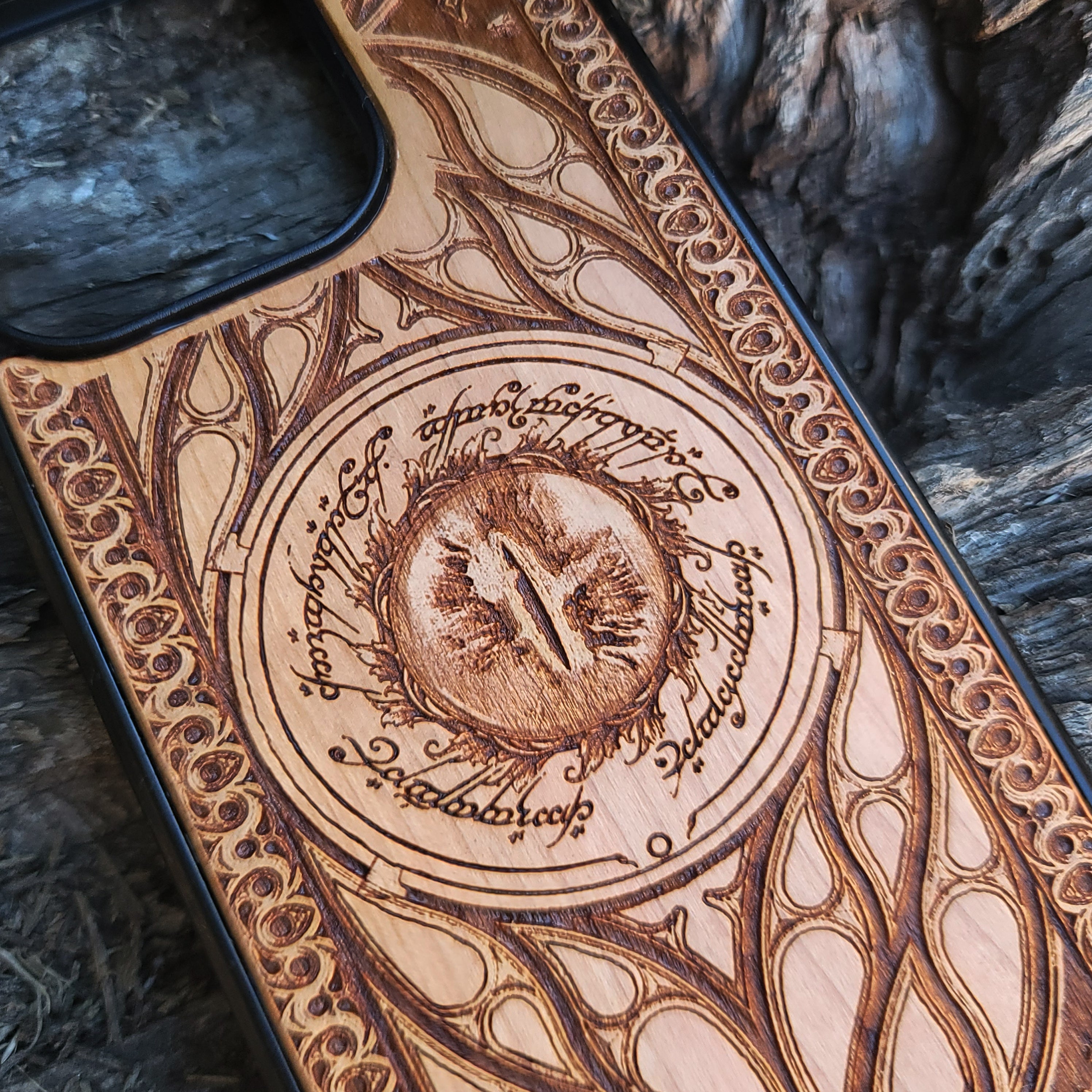 Lord of the Rings wood phone case featuring the Eye of Sauron surrounded by Elvish script and intricate, elegant patterns. Laser-engraved for durability and unique artistry, this case is compatible with iPhone , 15, 14, 13, 12, 11, Pro Max, Mini, and Samsung Galaxy S, S24, S23, S22, S21, S20 Ultra, Plus, Note 20. A stunning and protective accessory for Tolkien fans.