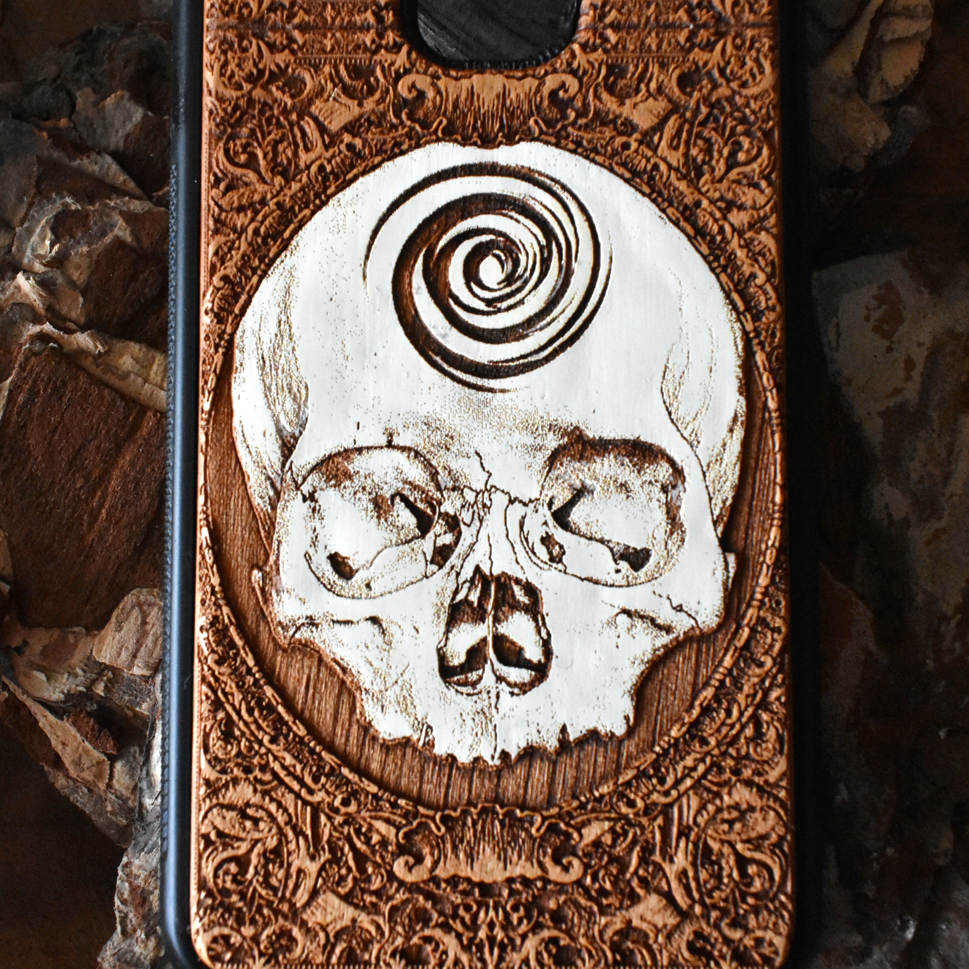 Laser-engraved skull art on a wooden phone case, compatible with iPhone 16, iPhone 15, Galaxy S25, and more.