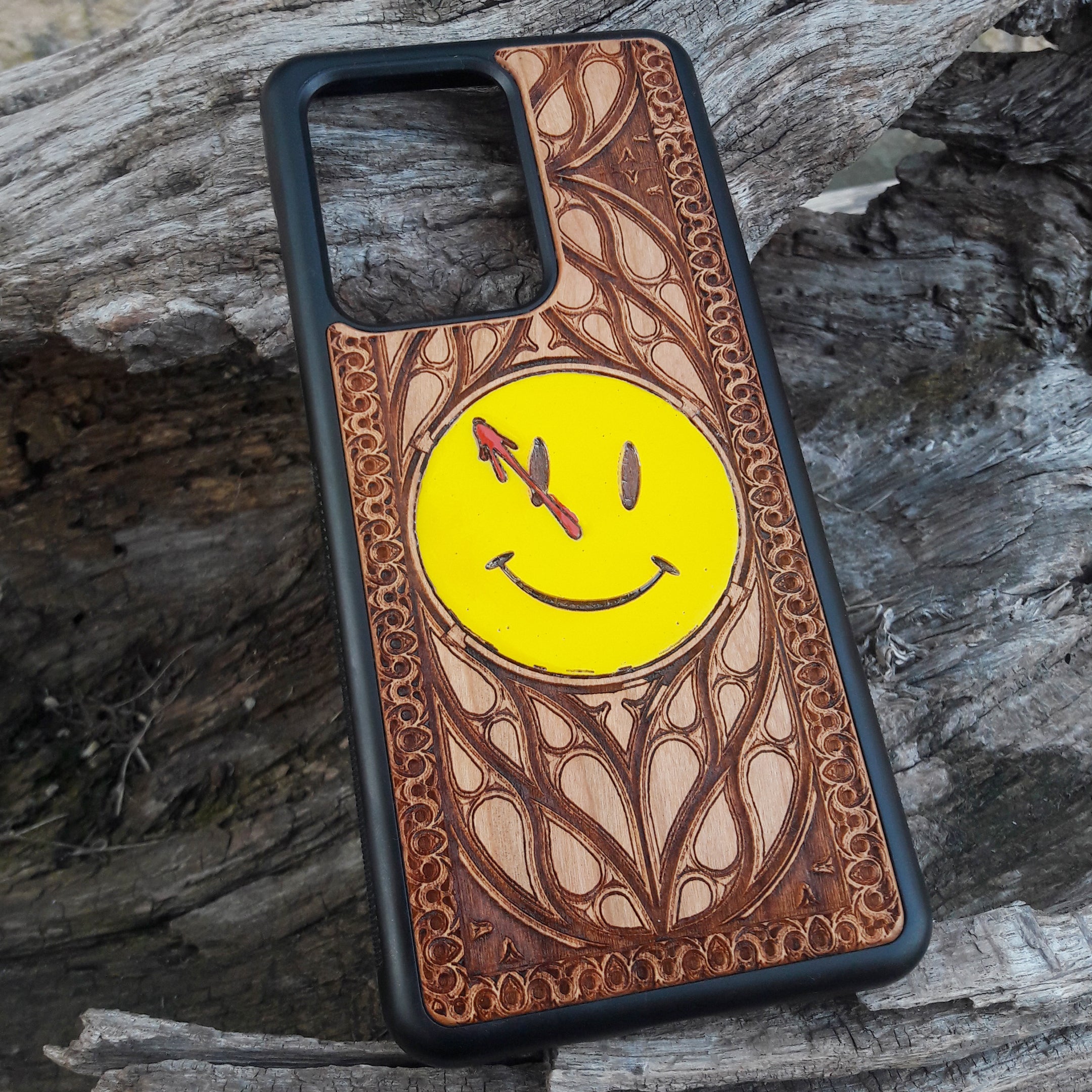Wooden phone case for iPhone and Samsung Galaxy featuring the 'Smiley' symbol from the Watchmen saga, laser-engraved for a unique touch. Compatible with iPhone 15, 14, 13, 12, 11 Pro Max Mini and Samsung Galaxy S24, S23, S22, S21, S20 Ultra Plus Note 20. Slim, durable, and stylish—order now to make a statement!