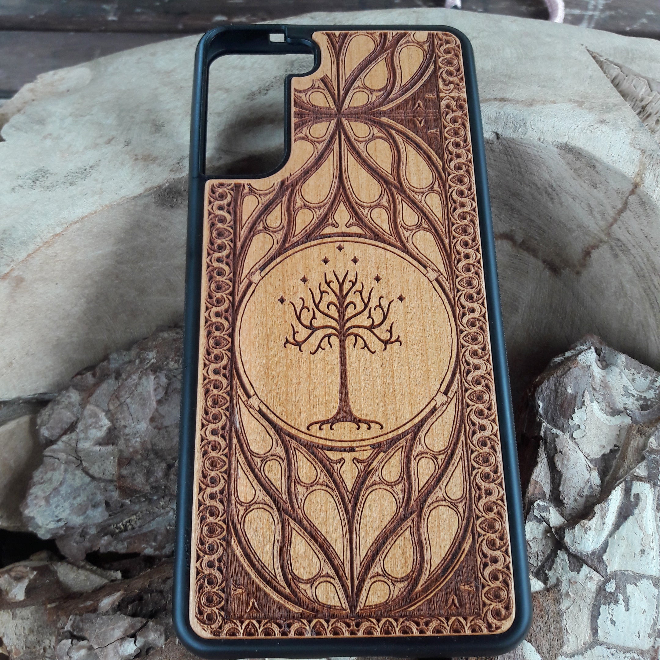Lord of the Rings wood phone case featuring the White Tree of Gondor with intricate Elvish-inspired patterns. Laser-engraved for elegance and durability, this case is compatible with iPhone , 15, 14, 13, 12, 11, Pro Max, Mini, and Samsung Galaxy S, S24, S23, S22, S21, S20 Ultra, Plus, Note 20. A stylish and protective accessory for Tolkien fans.