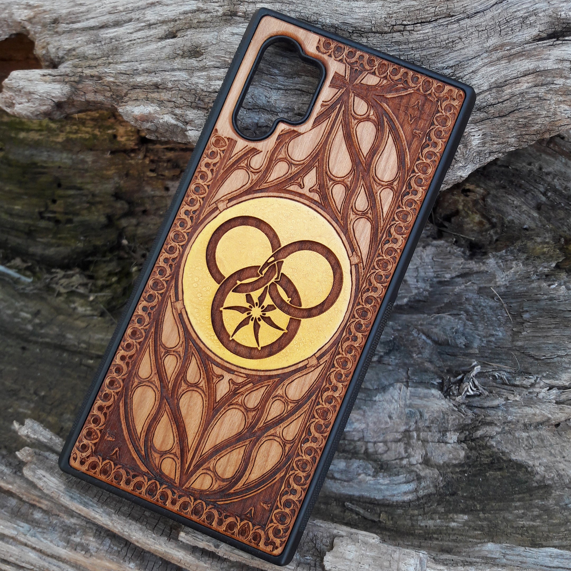 Wooden phone case featuring a detailed Wheel of Time-inspired design, showcasing intricate engravings of the Aes Sedai symbol and runes. The laser-engraved design captures the essence of Robert Jordan's iconic fantasy series. Compatible with iPhone , 15, 14, 13, 12, 11 Pro Max Mini, and Samsung Galaxy S, S24, S23, S22, S21, S20 Ultra, Plus, Note 20. A perfect, durable accessory for fans of the Wheel of Time series, blending art and protection.