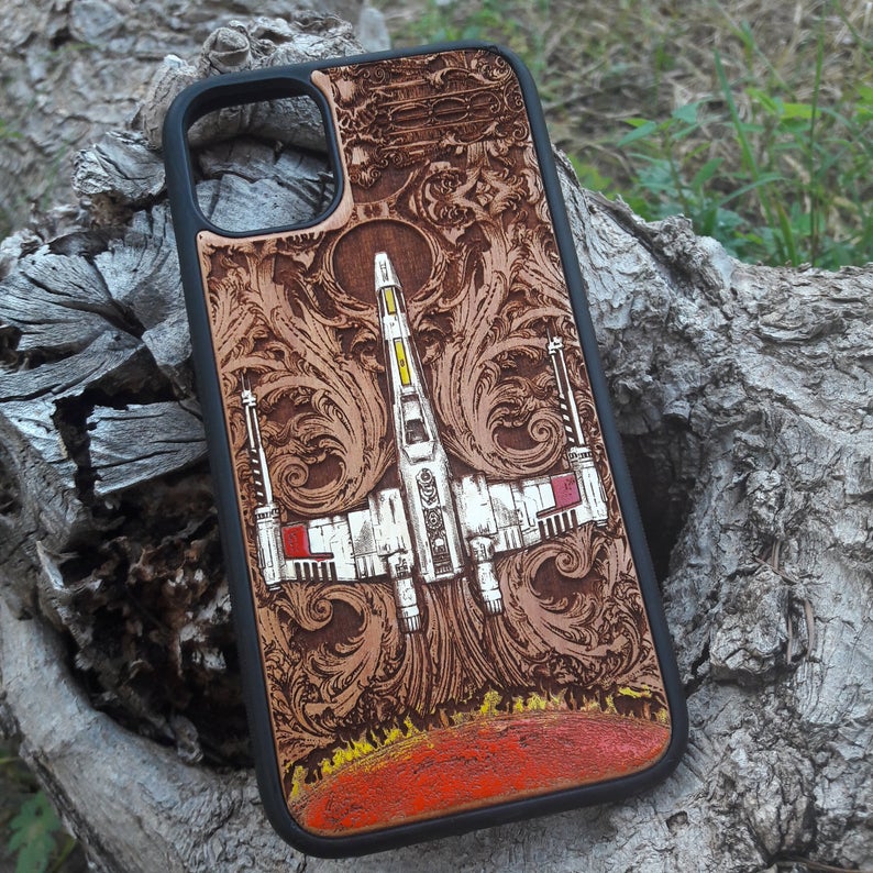 Close-up of handcrafted X-Wing Star Wars wooden phone case, hand-painted with intricate details on cherrywood. Fits iPhone & Galaxy models.