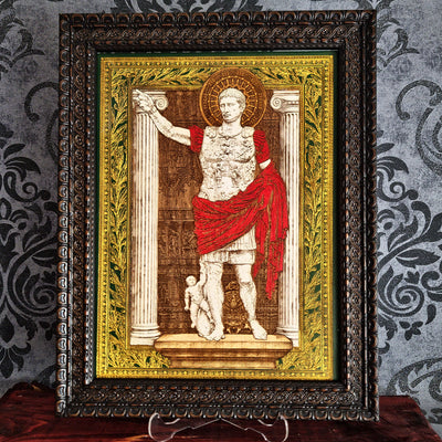 A framed art print depicting a Roman emperor standing before columns, with a red draped robe and a gold halo, set in an ornate dark frame against a patterned gray wall.