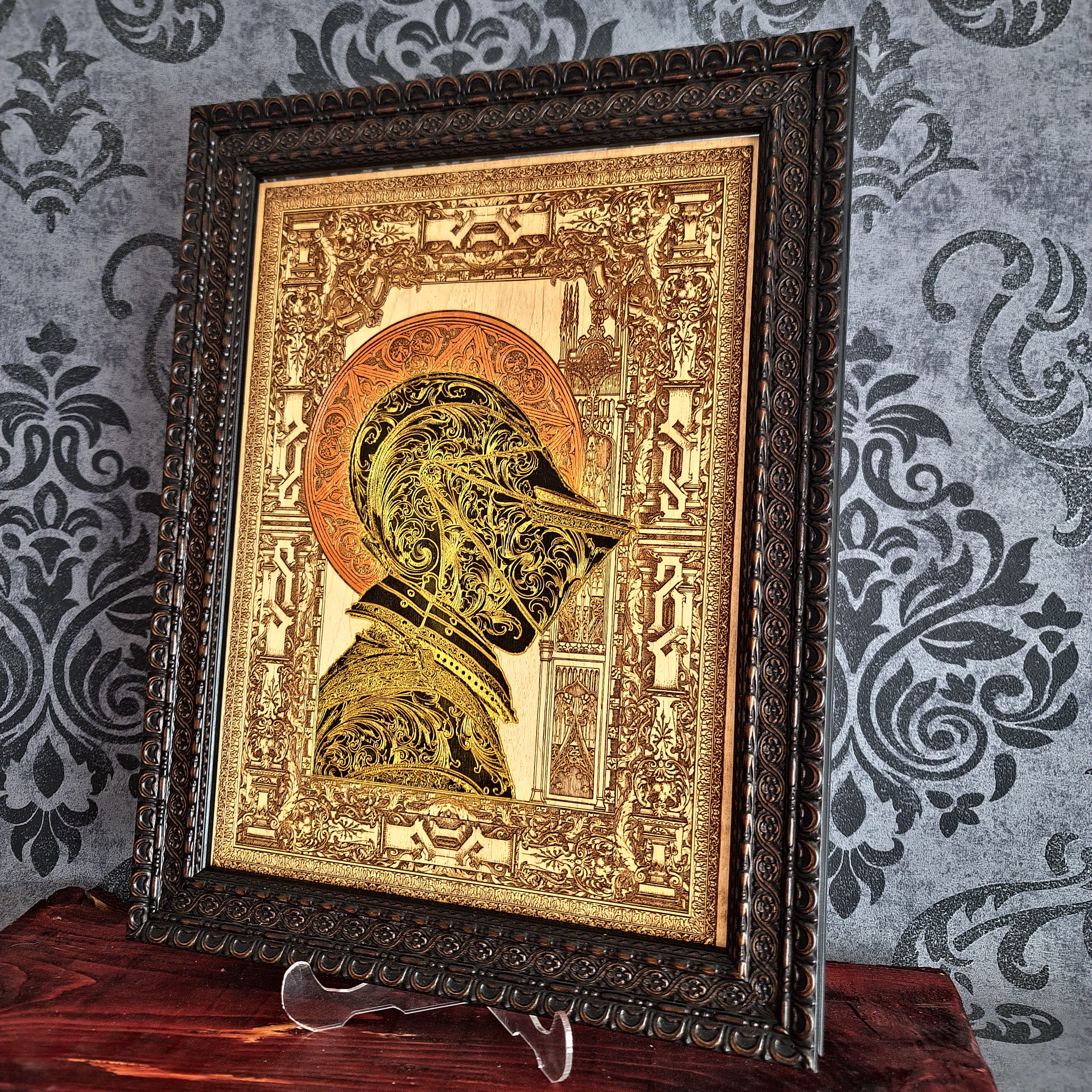 Black-and-gold medieval knight helmet maple wood wall art, angled view in an ornate dark brown frame