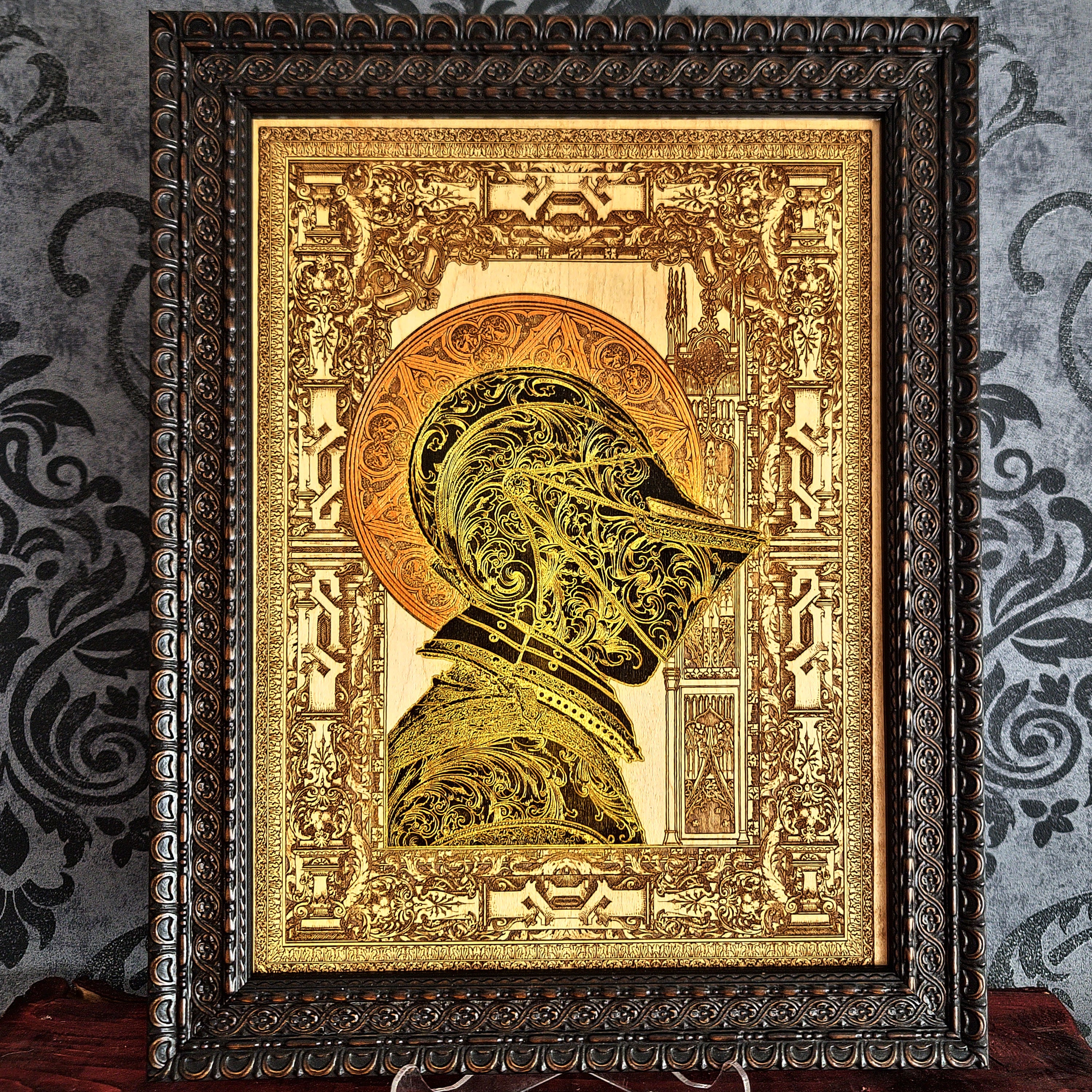 Black-and-gold medieval knight helmet maple wood wall art, front view in an ornate dark brown frame