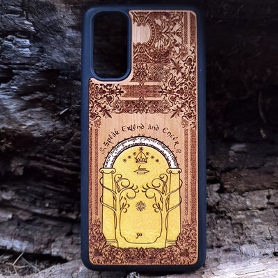 Wooden phone case featuring a gothic Lord of the Rings-inspired design of the Gate of Moria. The intricate laser-engraving showcases the iconic dwarven door from the Mines of Moria, adorned with Elvish script and decorative elements. Compatible with iPhone , 15, 14, 13, 12, 11 Pro Max Mini and Samsung Galaxy S, S24, S23, S22, S21, S20 Ultra, Plus, Note 20. A unique and durable accessory perfect for fans of Tolkien’s Middle-earth.
