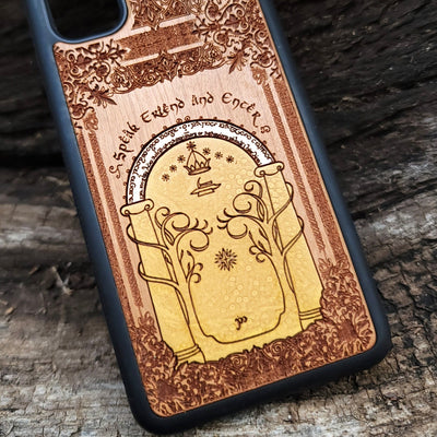 Wooden phone case featuring a gothic Lord of the Rings-inspired design of the Gate of Moria. The intricate laser-engraving showcases the iconic dwarven door from the Mines of Moria, adorned with Elvish script and decorative elements. Compatible with iPhone , 15, 14, 13, 12, 11 Pro Max Mini and Samsung Galaxy S, S24, S23, S22, S21, S20 Ultra, Plus, Note 20. A unique and durable accessory perfect for fans of Tolkien’s Middle-earth.