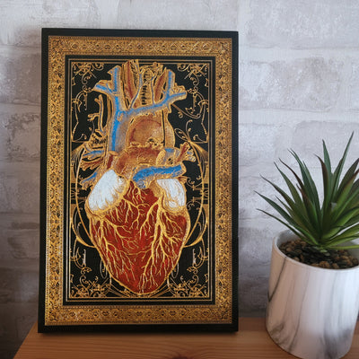 Black wood anatomical heart art with gold highlights, bold and dramatic.