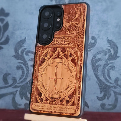 A wooden phone case featuring a sword and the inscription "Nanye, Anduril i ne Narsil i macil Elendilo. Lercuvanten i mali Mordoreo."