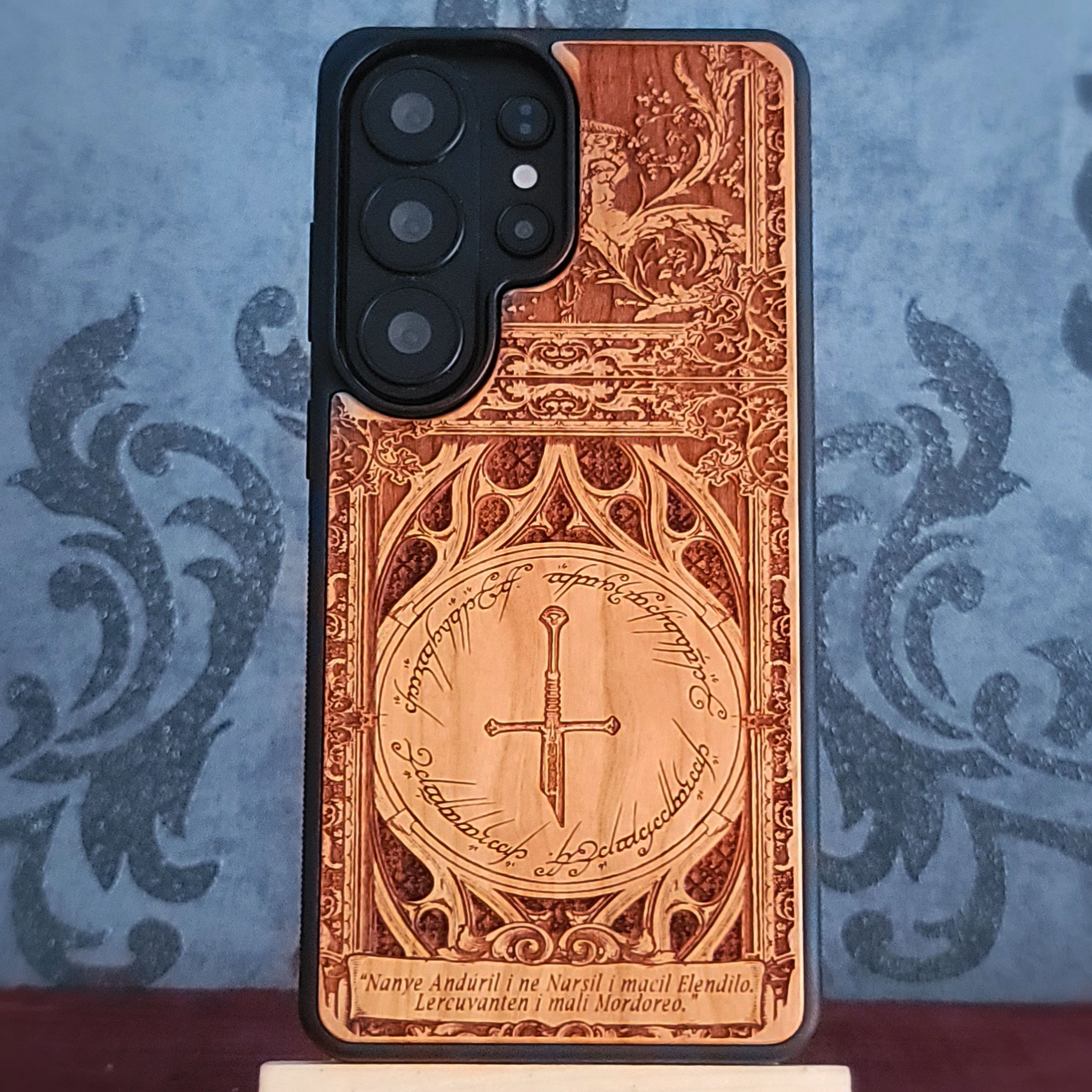 A wooden phone case featuring a sword and the inscription "Nanye, Anduril i ne Narsil i macil Elendilo. Lercuvanten i mali Mordoreo."