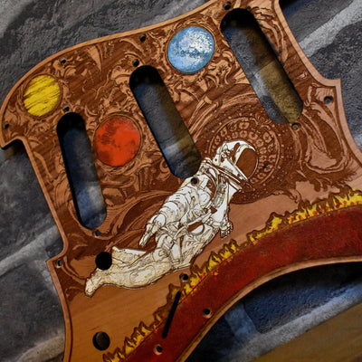 Close-up of laser-engraved cherry wood pickguard with detailed craftsmanship for Fender Strato.