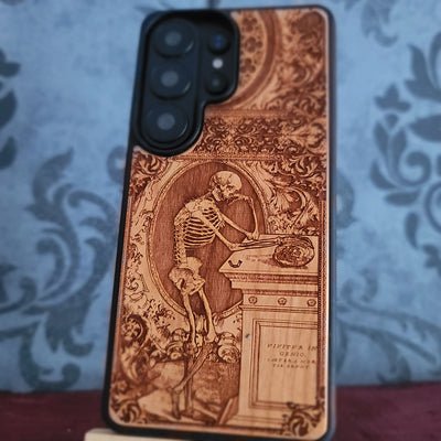 Laser-engraved wooden phone case with a gothic skeleton thinker design, perfect for iPhone and Samsung Galaxy.