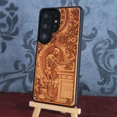 Laser-engraved wooden phone case with a gothic skeleton thinker design, perfect for iPhone and Samsung Galaxy.