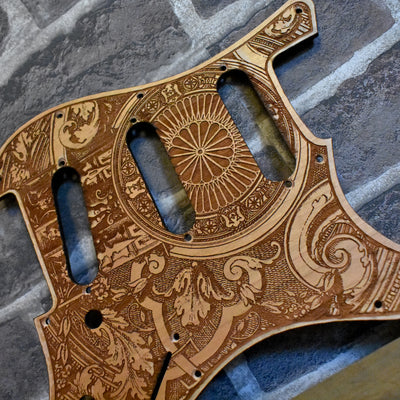 Close-up of laser-engraved cherry wood Fender Stratocaster pickguard with gothic artwork