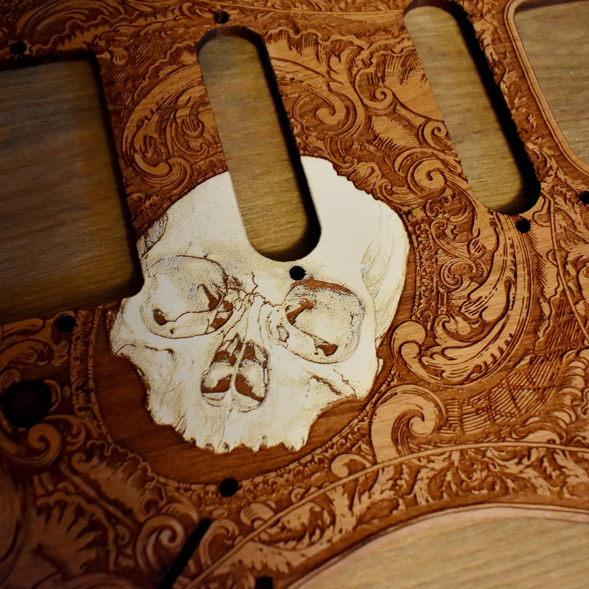 Close-up of handcrafted skull engraving on Fender Stratocaster wood pickguard