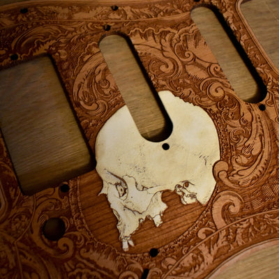 Custom cherry wood pickguard with skull engraving for Fender Stratocaster guitars.