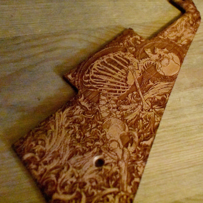 Close-up of laser-engraved cherry wood pickguard for Gibson Les Paul guitar.