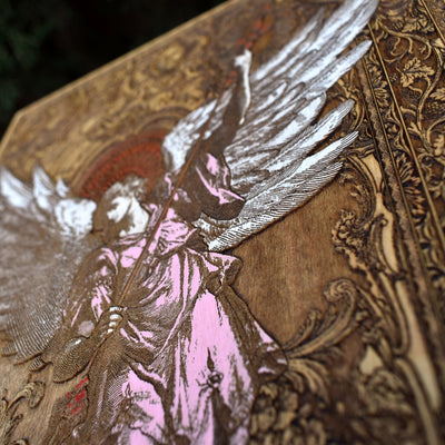 Laser-engraved Saint Michael Archangel with sword and shield on cedar wood.