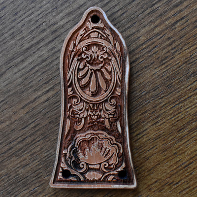 Laser‑engraved wood truss‑rod cover for an Epiphone‑style guitar. The wood has a warm medium‑brown finish with visible grain. The design features a horizontal band of elegant floral scrollwork across the centre. Two small screw mounting holes are visible at the bottom edge.