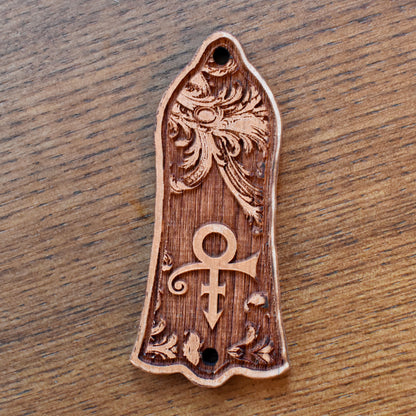 Custom cherrywood truss rod cover for Gibson Les Paul, featuring Prince inspired engraved symbol design, handcrafted by Engraver’s Dungeon.