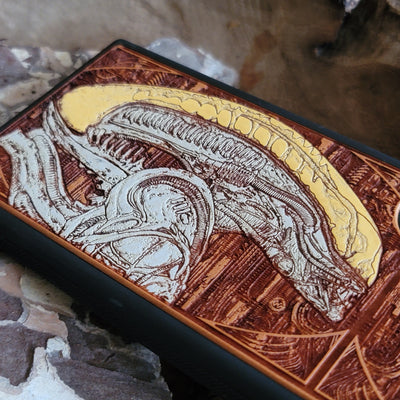 Alien-inspired gothic artwork engraved on a wooden phone case, compatible with iPhone and Samsung Galaxy