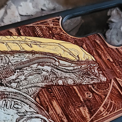 Alien-inspired gothic artwork engraved on a wooden phone case, compatible with iPhone and Samsung Galaxy