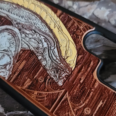 Alien-inspired gothic artwork engraved on a wooden phone case, compatible with iPhone and Samsung Galaxy