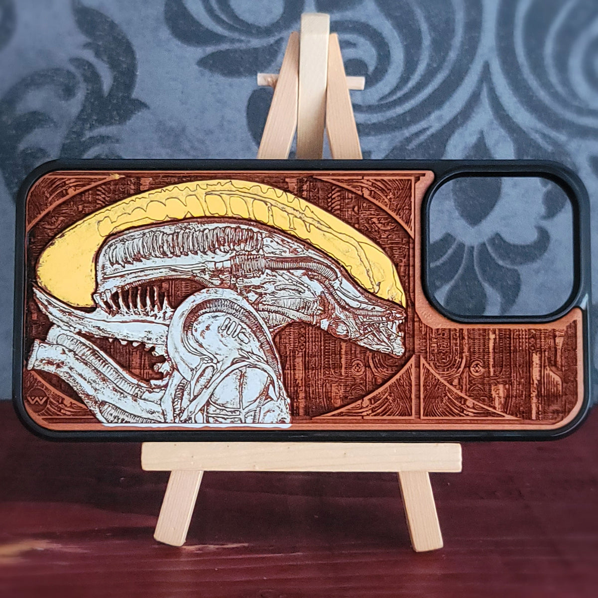 Alien-inspired gothic artwork engraved on a wooden phone case, compatible with iPhone and Samsung Galaxy
