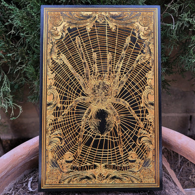 Goliath birdeater spider engraved in wood with black paint and gold pigment.