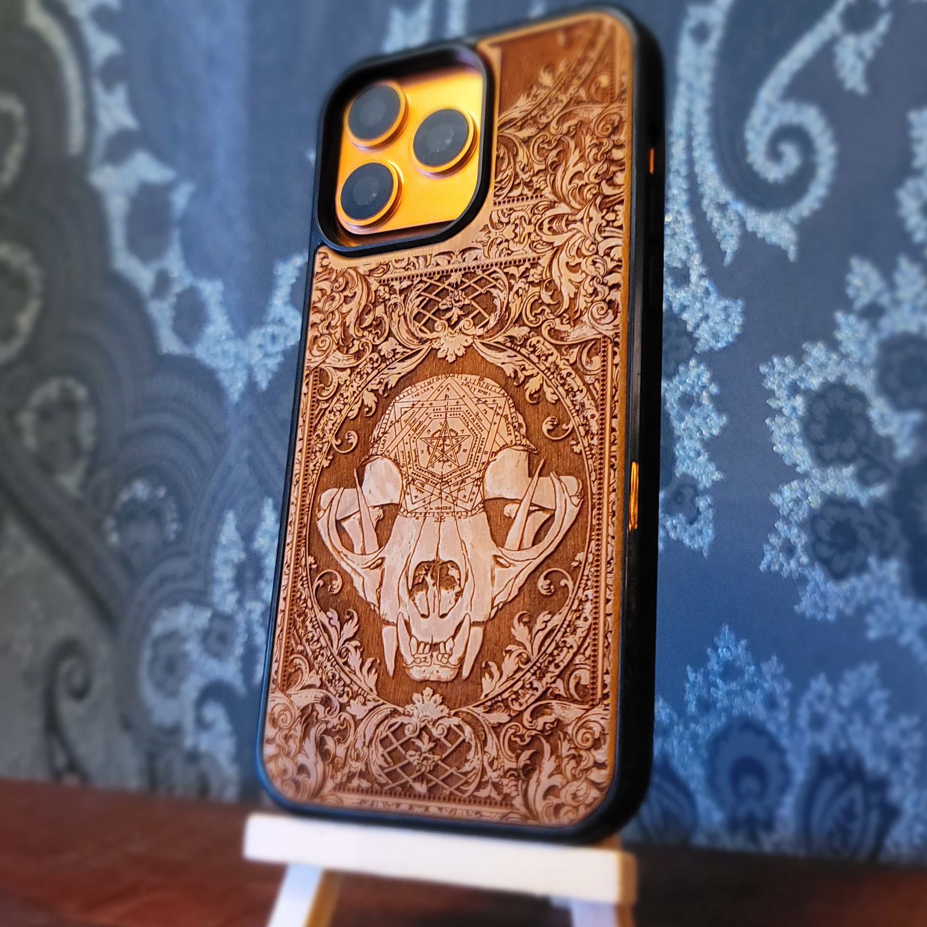 Deep laser engraved wooden phone case featuring a mystical cat skull design with witchy dark art details on natural wood for iPhone and Samsung Galaxy models.