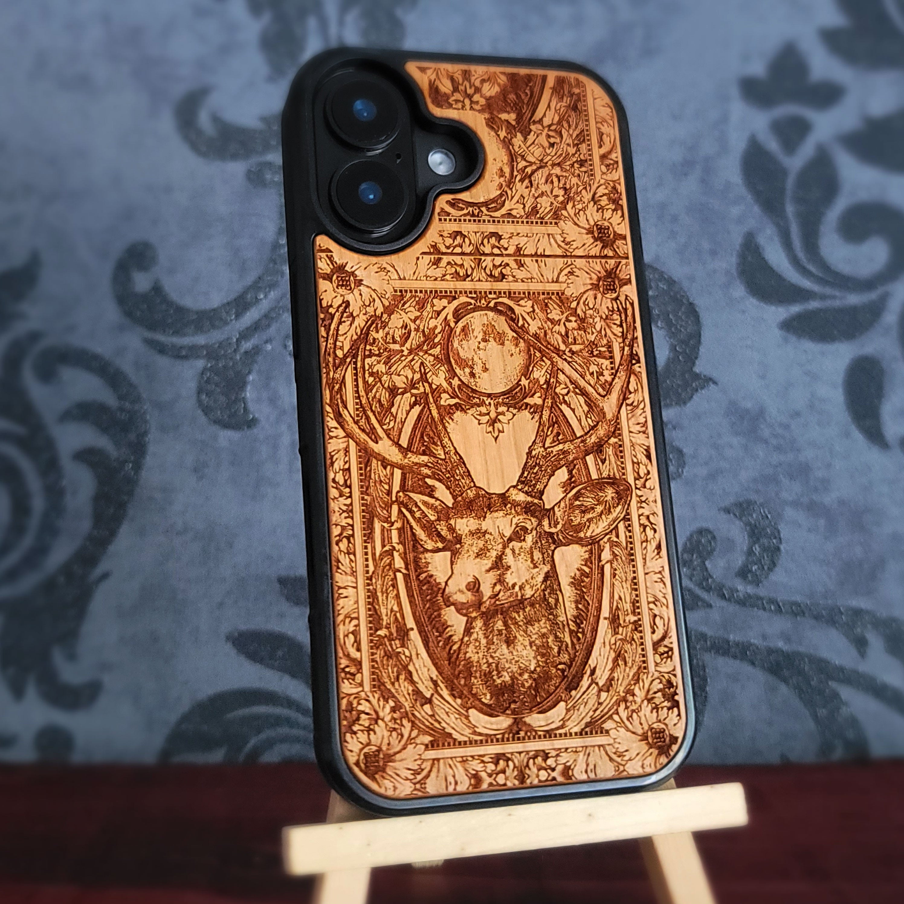 A wooden phone case with a detailed laser-engraved design of a stag 