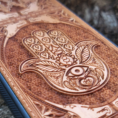 Wooden phone case featuring a beautifully intricate Hamsa hand design, intricately laser-engraved with fine detailing. The design is symbolic of protection, peace, and good fortune. Compatible with iPhone , 15, 14, 13, 12, 11 Pro Max Mini and Samsung Galaxy S, S24, S23, S22, S21, S20 Ultra, Plus, and Note 20. A unique and durable accessory perfect for those seeking a meaningful and stylish phone case.