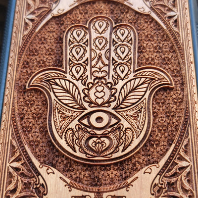Wooden phone case featuring a beautifully intricate Hamsa hand design, intricately laser-engraved with fine detailing. The design is symbolic of protection, peace, and good fortune. Compatible with iPhone , 15, 14, 13, 12, 11 Pro Max Mini and Samsung Galaxy S, S24, S23, S22, S21, S20 Ultra, Plus, and Note 20. A unique and durable accessory perfect for those seeking a meaningful and stylish phone case.