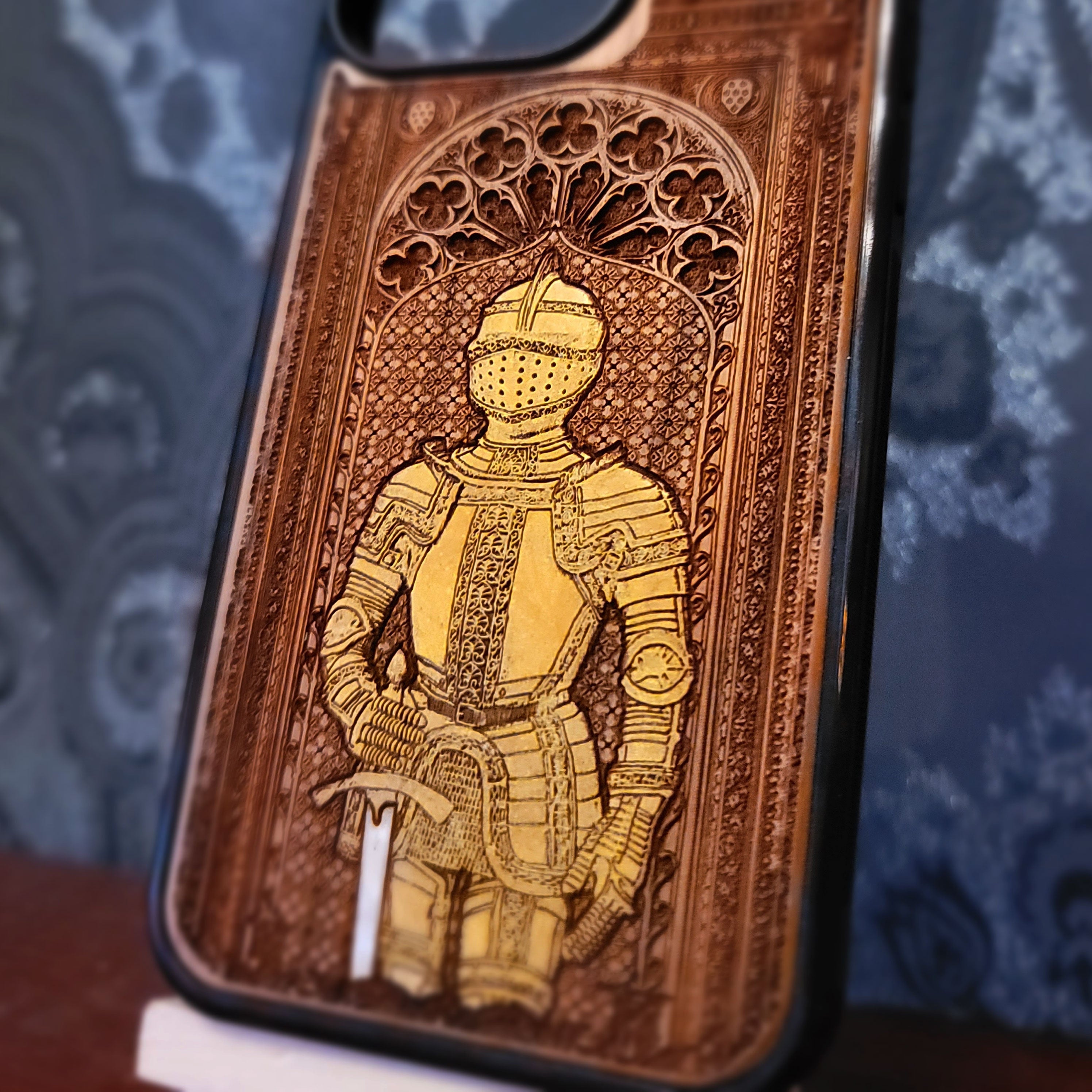 Deep laser engraved wooden phone case featuring a medieval knight in detailed armor holding a sword on natural wood for iPhone and Samsung Galaxy models.