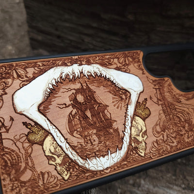 Close-up of handcrafted cherry wood phone case featuring a detailed shark engraving.