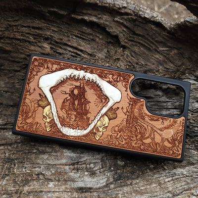 Close-up of handcrafted cherry wood phone case featuring a detailed shark engraving.