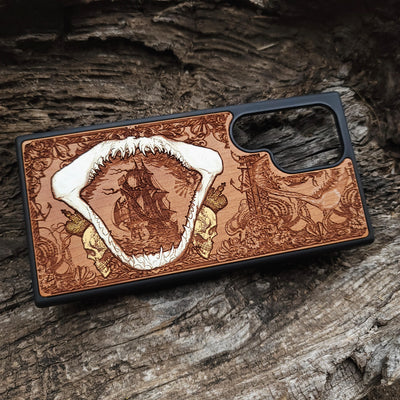 Close-up of handcrafted cherry wood phone case featuring a detailed shark engraving.