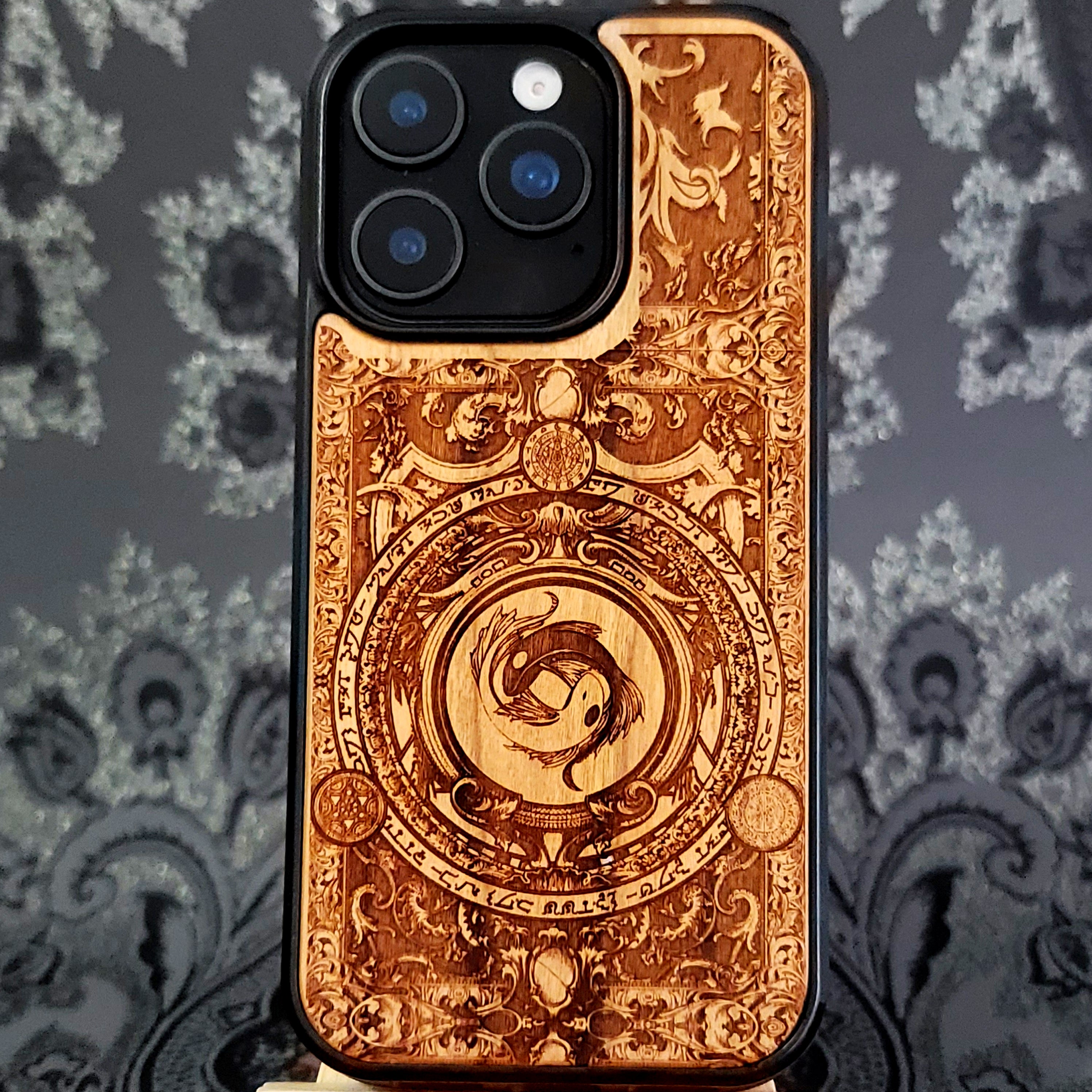 Deep laser engraved wooden phone case featuring two koi fish forming a yin yang symbol on natural wood for iPhone and Samsung Galaxy models.