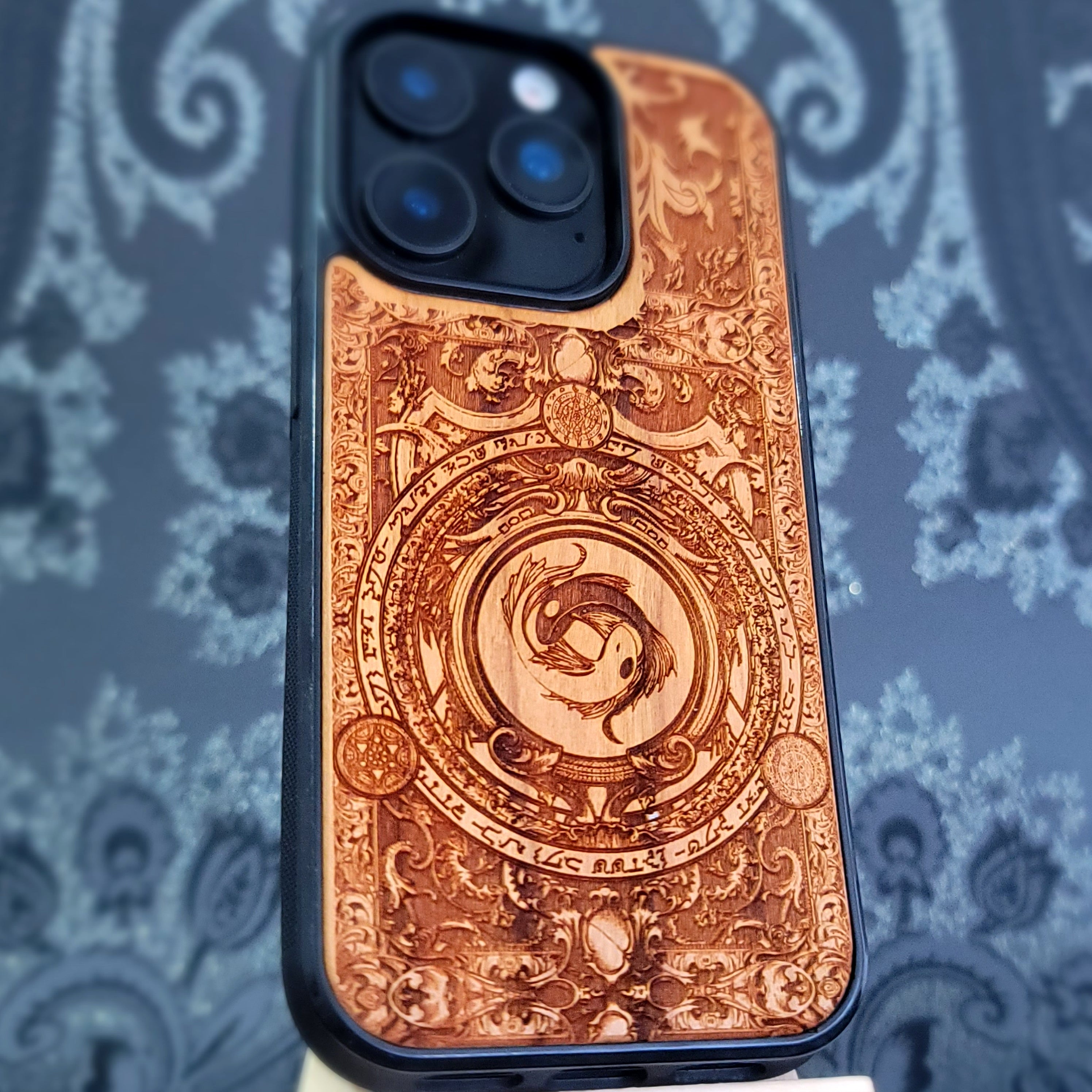 Deep laser engraved wooden phone case featuring two koi fish forming a yin yang symbol on natural wood for iPhone and Samsung Galaxy models.
