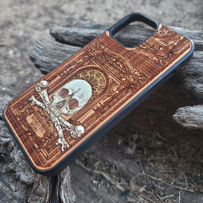 Hand-painted Memento Mori wooden phone case featuring a laser-engraved skull and bones design on cherrywood. Compatible with iPhone -11 Pro Max and Galaxy S-S20.