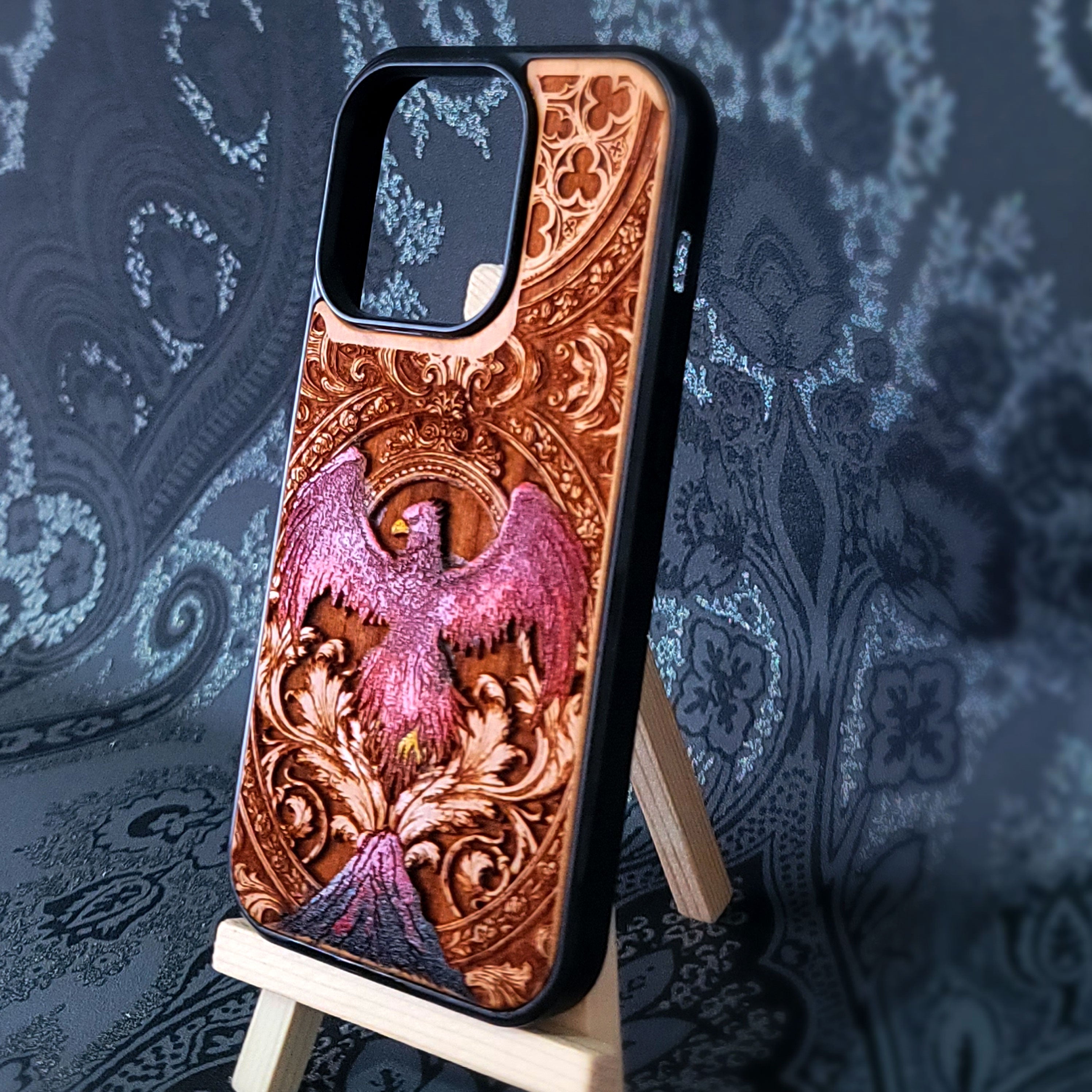 Deep laser engraved wooden phone case featuring a mythical phoenix bird with detailed flames and wings on natural wood for iPhone and Samsung Galaxy models.