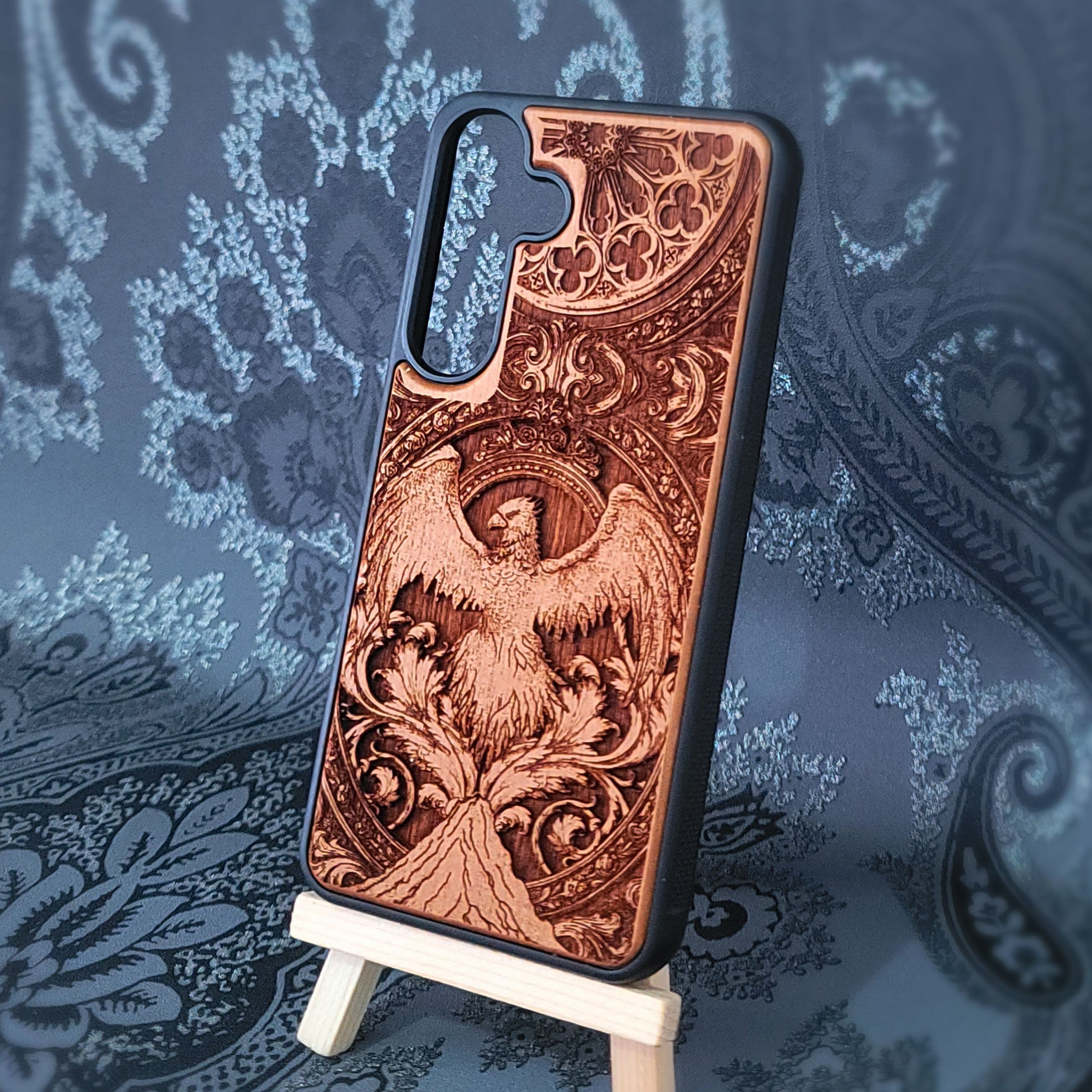Deep laser engraved wooden phone case featuring a mythical phoenix bird design on natural wood. Available for iPhone and Samsung Galaxy.