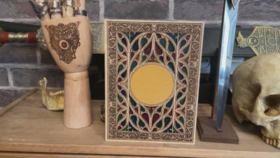 Stained glass-style gothic window engraving on wood with symbolic centerpiece.