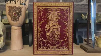 Detailed human heart anatomy painting in red on wood, enriched with gold interior accents.