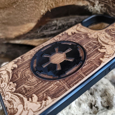 Wooden phone case with a detailed engraved sci-fi emblem resembling a galactic empire symbol, surrounded by ornate scrollwork, perfect for space opera fans