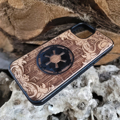 Wooden phone case with a detailed engraved sci-fi emblem resembling a galactic empire symbol, surrounded by ornate scrollwork, perfect for space opera fans